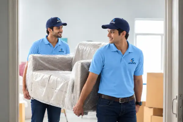 Shiftify movers carrying a wrapped armchair during house shifting